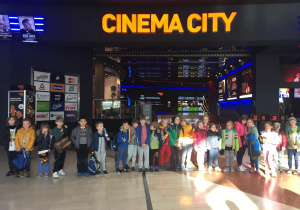 Uczniowie stoją w kinie Cinema City i pozują do zdjęcia grupowego.