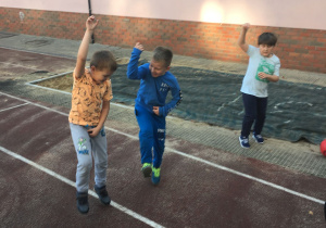 Trzej chłopcy tańczą na boisku szkolnym.