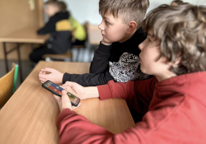 Leopold trzyma w ręku telefon i razem z Dominikiem zastanawiają się nad odpowiedzią.