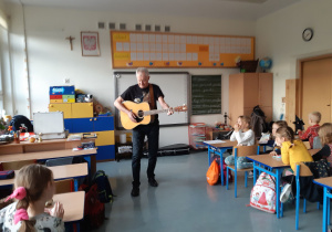 Uczniowie słuchają piosenki o zwierzętach zaśpiewanej i zagranej na gitarze przez Pana Tomasza.