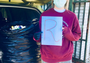 Uczennica naszej szkoły trzyma w ręku kartkę z literą r.