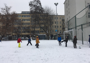 Chłopcy grają w piłkę nożną na śniegu.