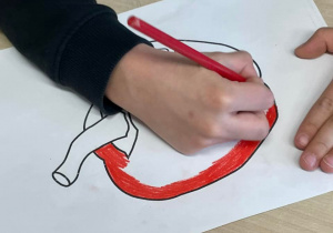 Uczeń koloruje czerwoną paprykę.