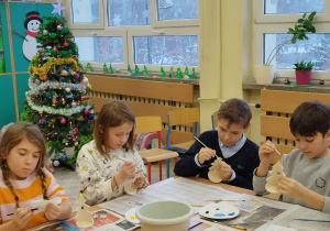 Dzieci z klasy trzeciej podczas malowania glinianych figurek.