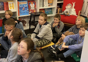 Uczniowie siedzą w księgarni i słuchają o patriotyźmie.