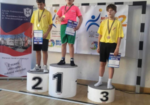 Uczniowie biorący udział w mistrzostwach stoja na podium podczas dekoracji medalami.