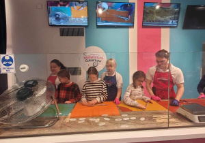 Kaja, Hania i Julia z pomocą prowadzących wyrabiają słodką masę na swoje lizaki.