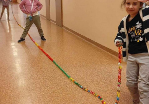 Dziewczynki prezentują długość łańcucha na korytarzu.