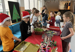 Uczniowie z klas trzecich pomagają w sprzedazy ozdób świątecznych.