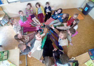 Dzieci siedzą w kółku z wyciągniętymi nóżkami i prezentują swoje kolorowe skarpetki.