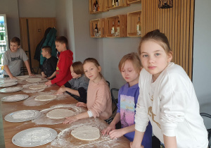 Uczniowie prezentują swoje gotowe ciasta do pizzy.
