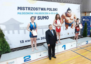 Kasia, po dekoracji medalami i wręczeniu dyplomów stoi na podium, na pierwszym miejscu.