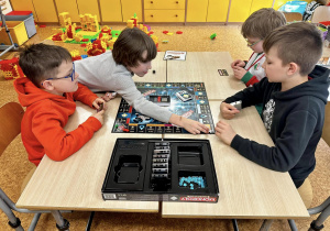 Chłopcy siedzą przy stoliku i grają w Monopoly Banking.