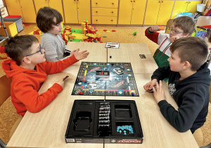 Chłopcy siedzą przy stoliku grają w Monopoly Banking.