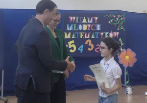 Julia odbiera dyplom i nagrodę z rąk organizatorów olimpiady.