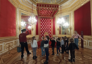 Dzieci z Panią Magdą oddają pokłon królowi w sali Tronowej.