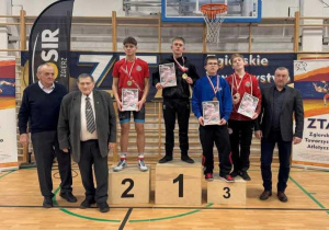 Adam stoi na podium podczas dekoracji medalami.