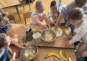 Dziewczynki przygotowują masę z bananów.