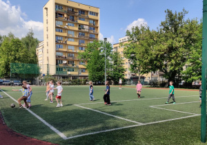 Uczniowie rozgrywają mecz na boisku.