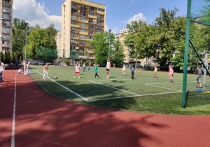 Uczniowie rozgrywają mecz na boisku.