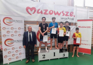 Karol stoi na podium podczas dekoracji medalami i dyplomami.