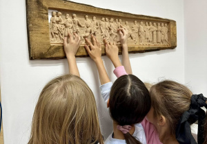 Trzy dziewczynki dotykają obrazek wykonany ploterem frezującym i podziwiają precyzję z jaką został wykonany..