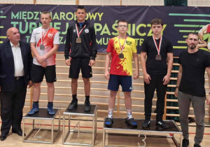 Adam stoi na podium podczas dekoracji medalami.