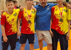 Nasi sportowcy wraz z trenerem pozują do wspólnego zdjęcia.