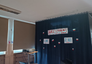 Dekoracja konkursowa - napis "Warszawa 1944" i dwie ważne daty: 1 siernia 1944 oraz 2 października 1944 - wiszą na granatowym tle.