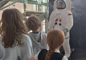 Dzieci pozują do zdjęć w skafandrze.