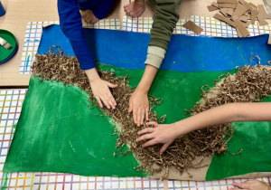 Uczniowie przyklejają tekturowe wypełnienie, które imituje ścieżkę w parku.