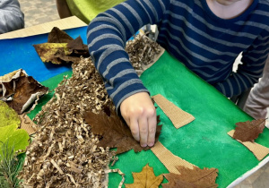 Uczniowie przyklejają liście, jako korony drzew.