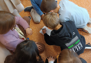 Uczniowie rozwiązują zagadkę na korytarzu.