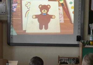 Uczniowie oglądają Misia narysowanego z kółek.