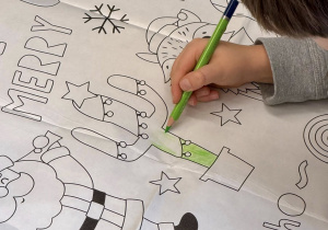 Chłopiec koloruje świątecznie ozdobionego kaktusa.