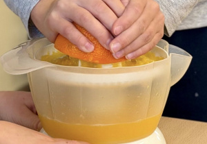 Chłopiec wyciska sok z pomarańczy.