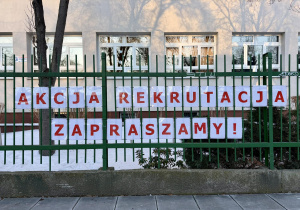 Akcja Rekrutacja. Zapraszamy! - napis ułożony z czerwonych liter wisi na parkanie szkoły.