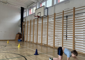 Uczeń na czworakach pokonuje slalom.