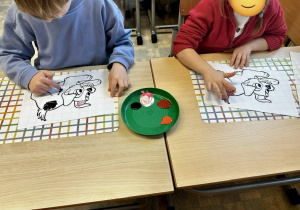 Uczniowie malują palcami kolorowanki z podobizną kundelka, która do złudzenia przypomina zakochanego kundla.