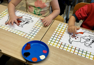 Uczniowie malują palcami kolorowanki z podobizną kundelka, która do złudzenia przypomina zakochanego kundla.