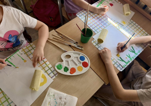 Uczniowie malują farbami.