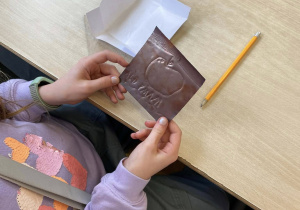 Uczennica ogląda swoją pracę plastyczną.