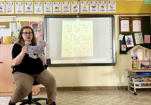 Wolontariuszka wykorzystując maskotkę kota pokazuje i tłumaczy uczniom "ocią mowę".