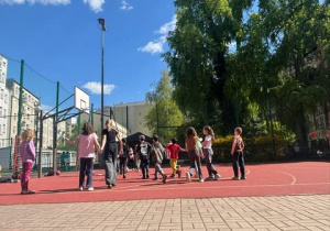 Uczniowie podczas zabawy sportowej na boisku szkolnym.