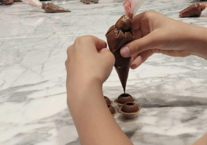 Manufaktura Cukierków - uczennica wypełnia swoje słodycze płynną czekoladą.